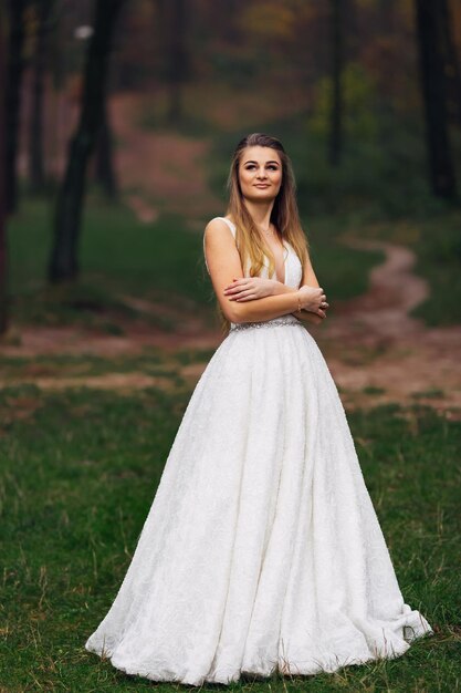 La sposa in un bellissimo abito da sposa ha incrociato le braccia e ha guardato