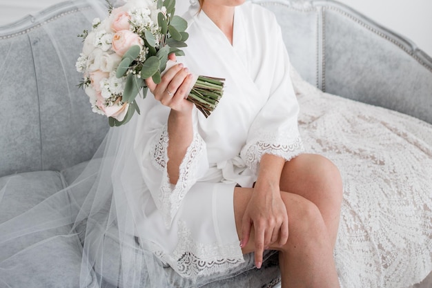 la sposa in veste bianca al mattino tiene in mano un bouquet