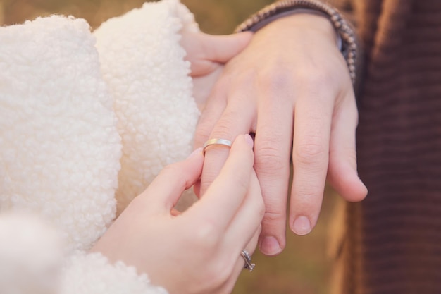 La sposa mette l'anello al dito dello sposo. Sera d'inverno, fuori. Messa a fuoco selettiva.