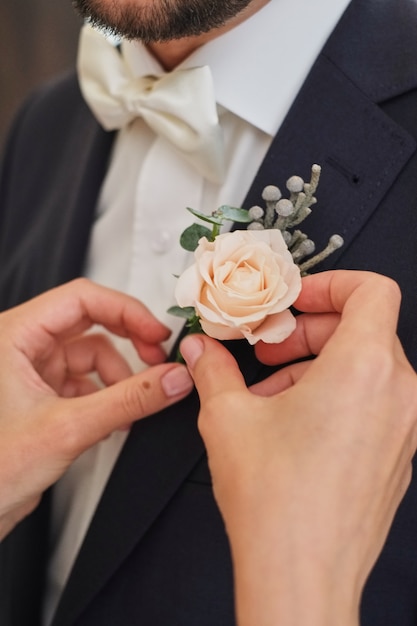 La sposa raddrizza lo sposo boutonniere luce rosa rosa