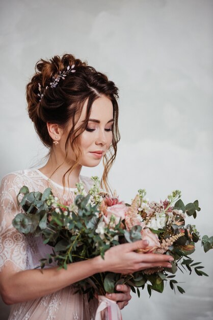 La sposa si riunisce al mattino in una vestaglia trasparente. Bouquet da sposa molto bello in rosa.