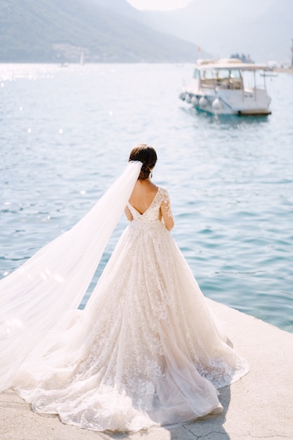 La sposa si trova sul molo della città di Perast in Montenegro e ammira le montagne e