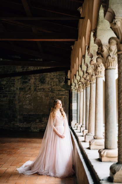 La sposa si trova vicino alle colonne del balcone di un'antica villa sul lago di como in italia