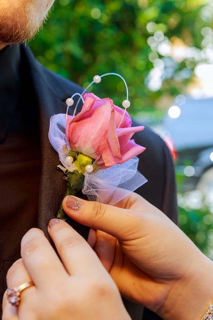 La sposa spilla un boutonniere alla giacca blu dello sposo