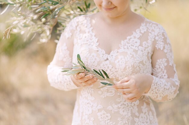 La sposa sta con un ramoscello d'ulivo in mano sotto un albero