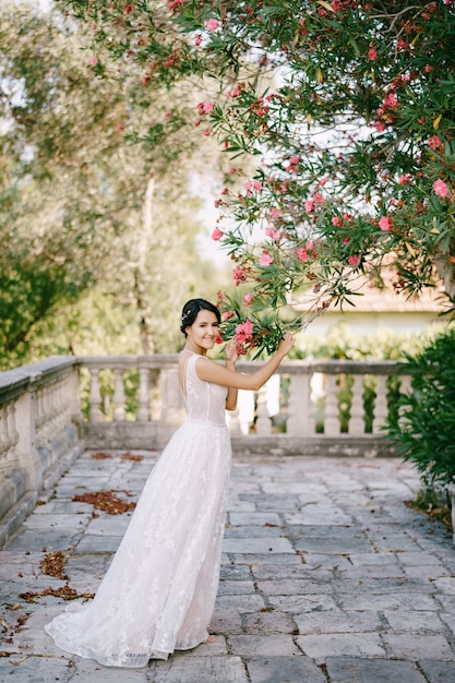 La sposa sta sotto un oleandro in fiore vicino alla vecchia chiesa e lo tocca
