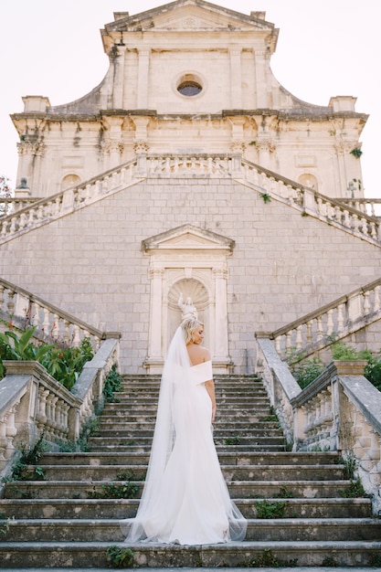 La sposa sta sui gradini di pietra della vista posteriore della cattedrale