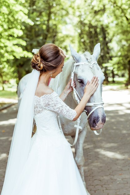 La sposa sta vicino al cavallo bianco