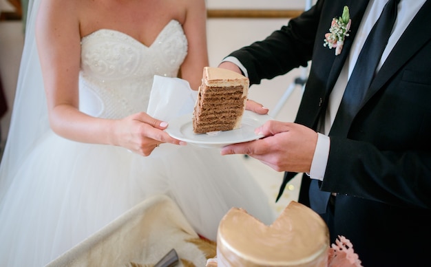 La sposa tiene il piatto mentre lo sposo lo mette pezzo di torta nunziale deliziosa