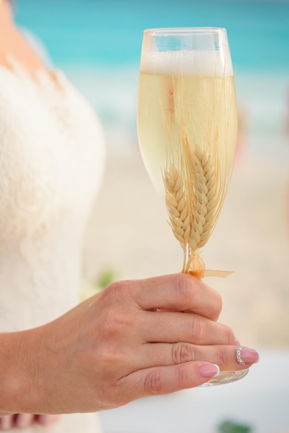 La sposa tiene in mano un bicchiere di champagne un primo piano di vetro