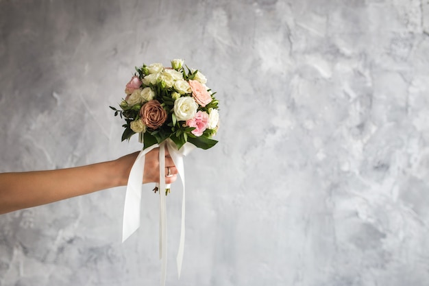 La sposa tiene in mano un bouquet da sposa su grigio