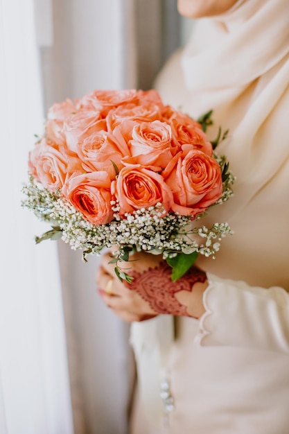 La sposa tiene in mano un bouquet da sposa.