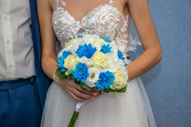 La sposa tiene in mano un magnifico bouquet da sposa durante la cerimonia