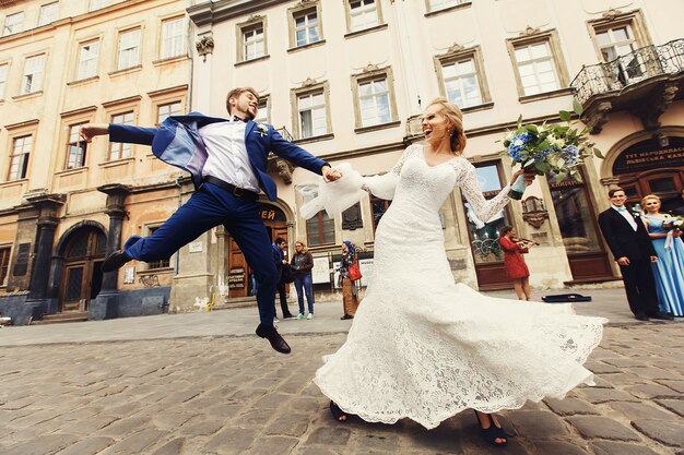 La sposa tiene la mano dello sposo mentre vola dietro di lei