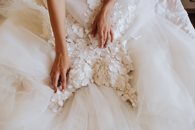 La sposa tocca il suo abito da sposa bianco