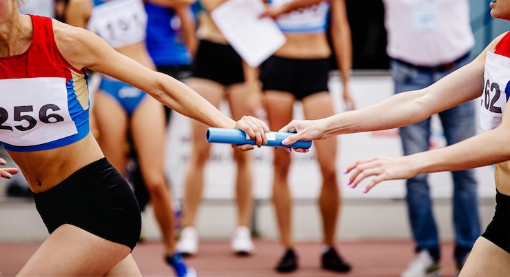 Foto la squadra femminile di staffetta passa la bacchetta correndo 4x400 metri