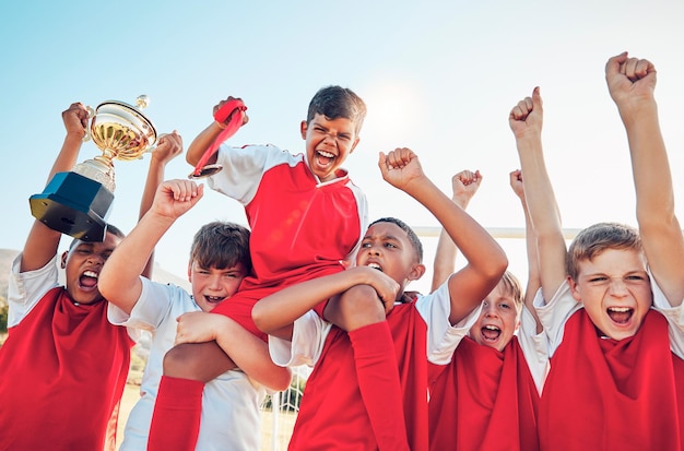 La squadra vincitrice di calcio e la celebrazione del trofeo sportivo sotto il sole insieme dopo una gara o una competizione di gioco Bambini felici e grida per vincere con la diversità e il successo nello sport dei ragazzi