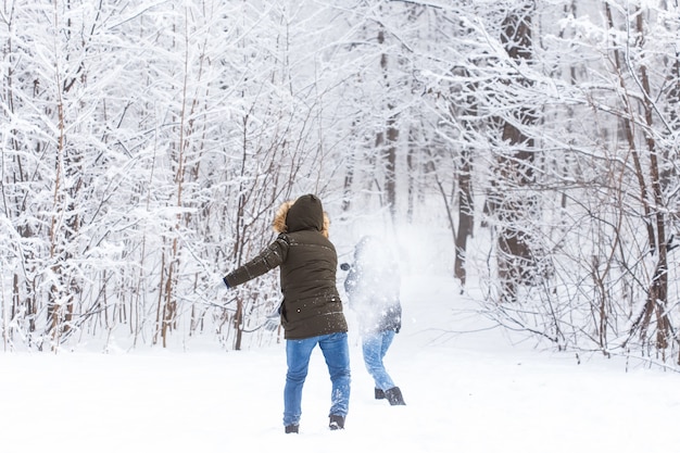 La stagione dello stile di vita e il concetto di svago coppie divertenti che giocano a palla di neve nel parco invernale