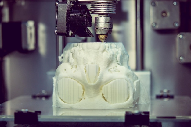 La stampante 3D stampa la forma di un primo piano bianco di plastica fusa. La stampante 3D tridimensionale automatica esegue la modellazione plastica in laboratorio. Tecnologia additiva moderna e progressiva