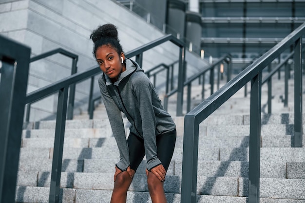 La stanca si prende una pausa La giovane donna afroamericana in abiti sportivi si allena all'aperto durante il giorno