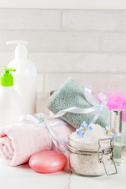 La stazione termale si rilassa e concetto del bagno, sale marino, sapone, con i cosmetici e gli asciugamani nella scena di bianco del bagno