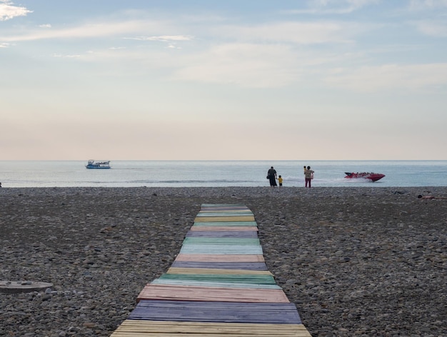 La strada dalle assi multicolori alla riva del mare Gente sulla costa Riposa sul mare