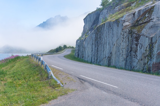 La strada è piegata intorno alla scogliera contro le montagne, Norvegia