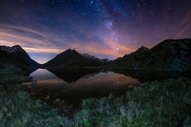 La straordinaria bellezza dell'arco della Via Lattea e il cielo stellato si riflettono sul lago in alta quota sulle Alpi.