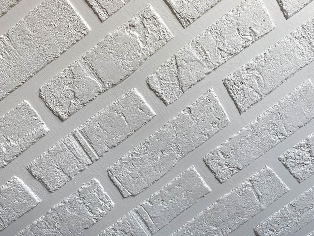 La struttura superficiale di un muro di mattoni in stile loft bianco fatto in casa con cuciture in mattoni di gesso