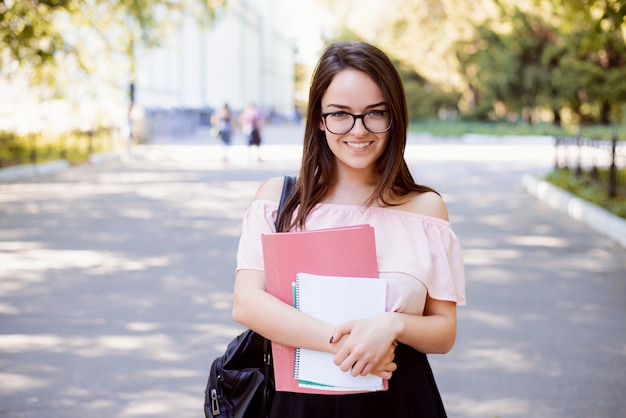 La studentessa allegra con i libri e le note va dall'università dopo le lezioni felici di avere buona giornata di studio