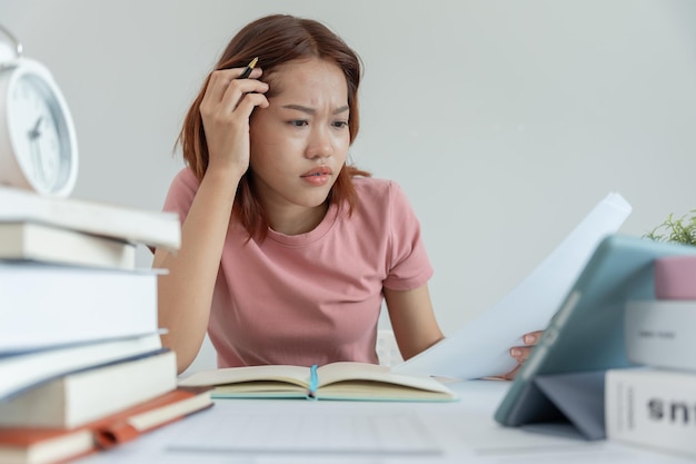 La studentessa asiatica ha ansia a causa degli esami, la donna si prepara per il test e apprende le lezioni in biblioteca, lo stress, la disperazione, la fretta, l'incomprensione, la lettura, l'aspettativa scoraggiata, la conoscenza