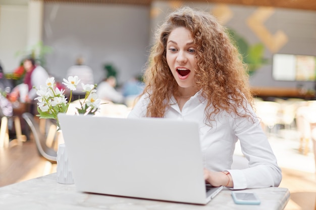 La studentessa attraente sorpresa lavora al computer portatile