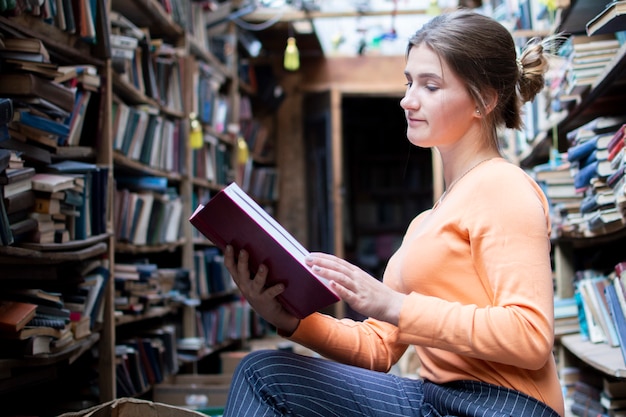 La studentessa legge un libro in una vecchia biblioteca