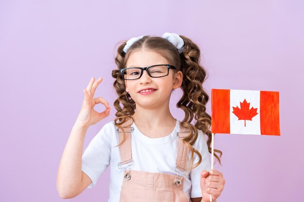 La studentessa sorride e tiene in mano la bandiera del Canada. anniversario della confederazione, sfondo isolato, giorno del canada,
