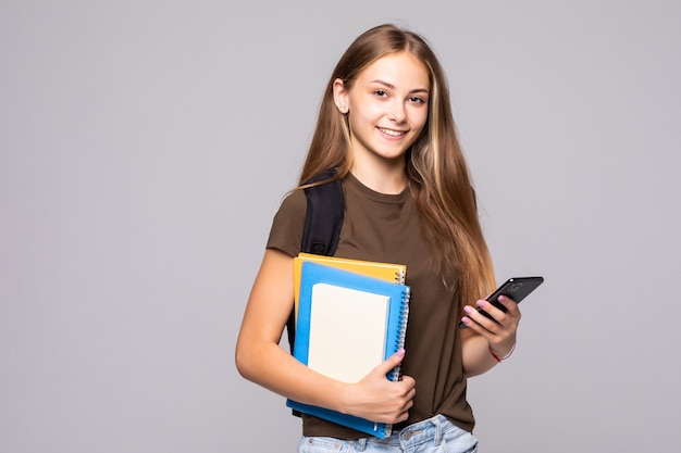 La studentessa sorridente felice utilizza il telefono isolato sul muro bianco