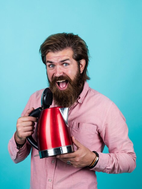 La sua scelta felice hipster con baffi bollire acqua maschio famiglia bere tè concetto uomo barbuto in camicia tenere bollitore elettrico ragazzo casual utilizzare la tecnologia moderna nella vita di tutti i giorni