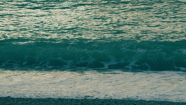 La superficie del mare piccole onde vista contro del sole dorato grande sole rosso caldo nell'aria calda sopra l'oceano