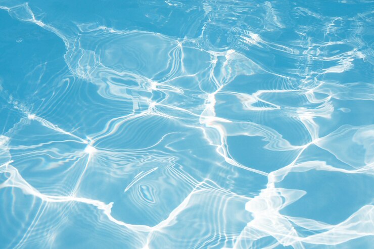 La superficie dell'acqua blu con le riflessioni leggere del sole luminoso, innaffia in primo piano del fondo della piscina