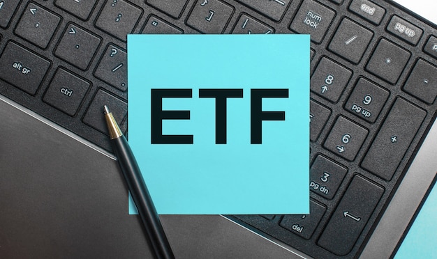 La tastiera del computer ha una penna e un adesivo blu con il testo ETF Exchange Traded Funds. Disposizione piatta.