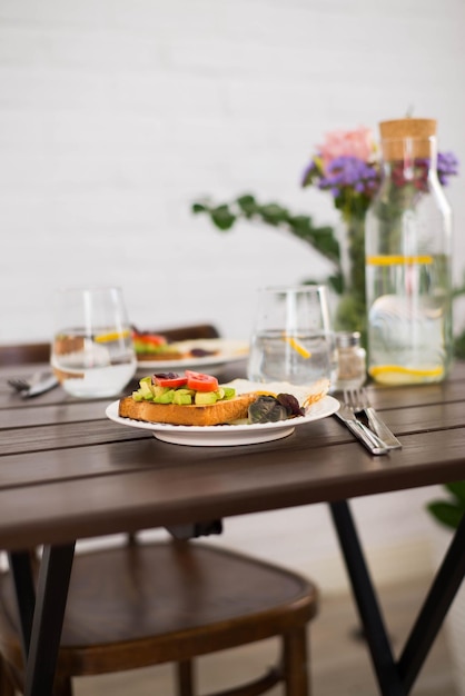 La tavola con colazione a base di panini e uova fritte bicchieri d'acqua al limone