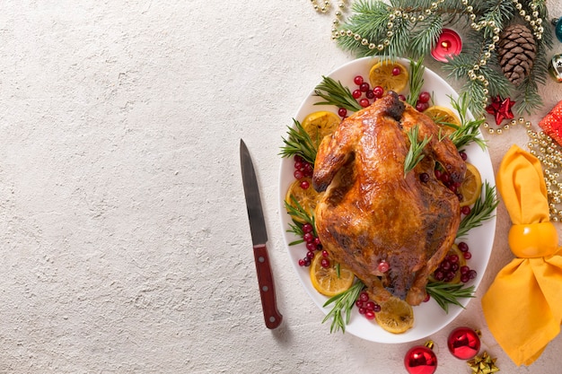 La tavola di Natale con pollo al forno è addobbata a festa con candele.