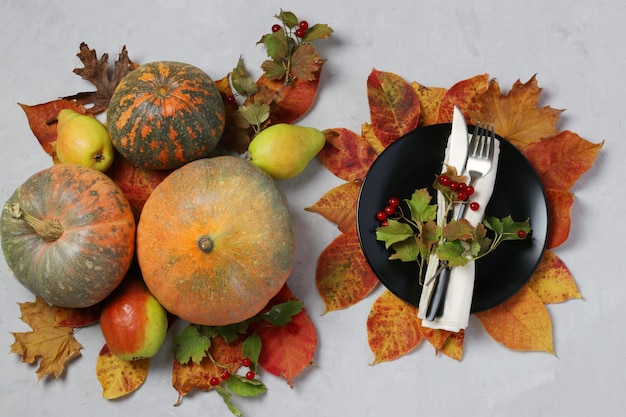 La tavola per il Giorno del Ringraziamento ha decorato la zucca, il viburno, le pere e le foglie colorate sulla superficie grigia. Vista dall'alto