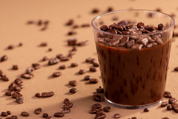 La tazza acrilica con brigadeiro e cioccolato spruzza su fondo marrone