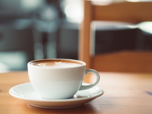 La tazza bianca di caffè caldo è servito sulla tavola di legno nel caffè.