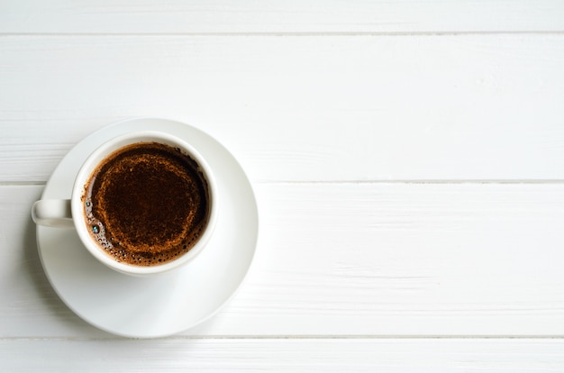 La tazza bianca di caffè nero su bianco ha dipinto il fondo di legno