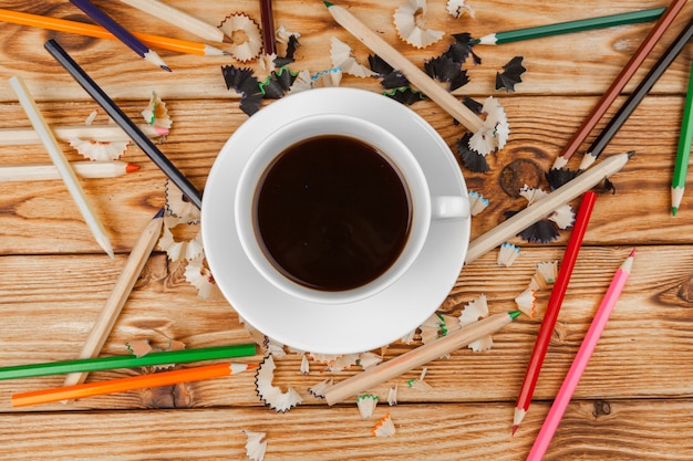 La tazza di caffè con le matite e la matita taglia su di legno