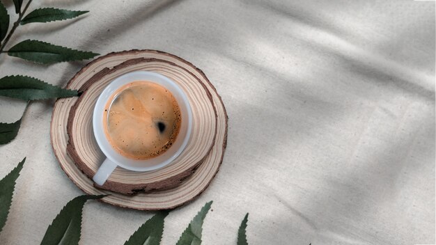 La tazza di caffè nera del primo piano ha messo sulla vista superiore del tessuto di lino