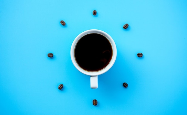 La tazza di caffè nero su sfondo blu con i chicchi di caffè si dispone come formando il quadrante dell'orologio