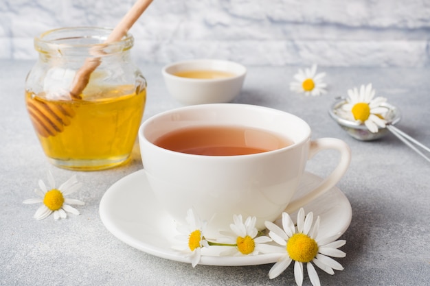 La tazza di tisana con la camomilla fiorisce sulla tavola grigia. Copia spazio