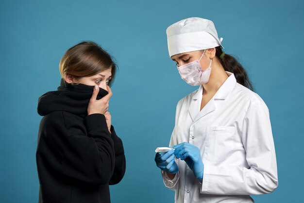 La temperatura di misurazione di un giovane medico con il termometro, studio ha sparato sul blu